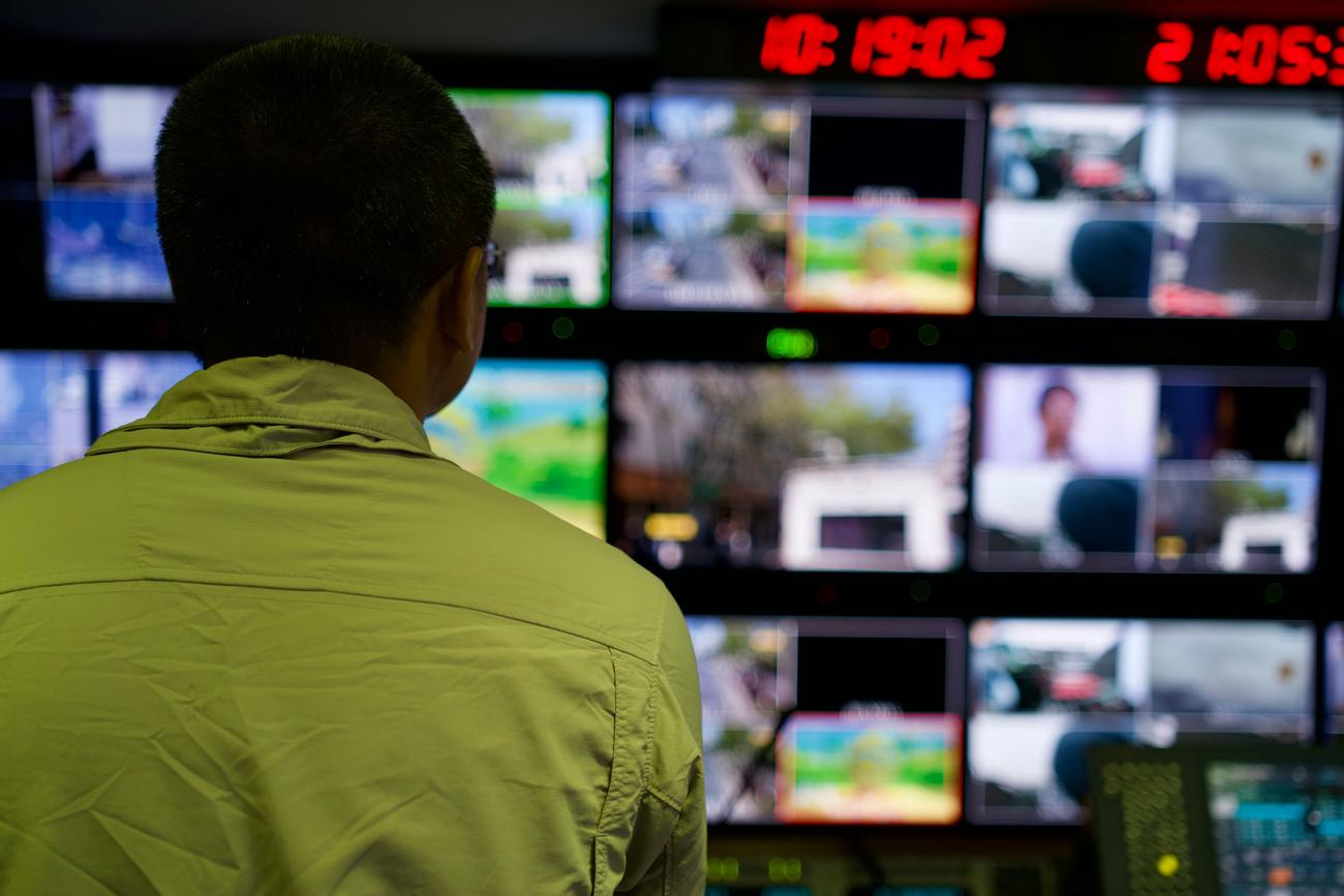 Operator at the control desk facing a monitoring wall — TV capture